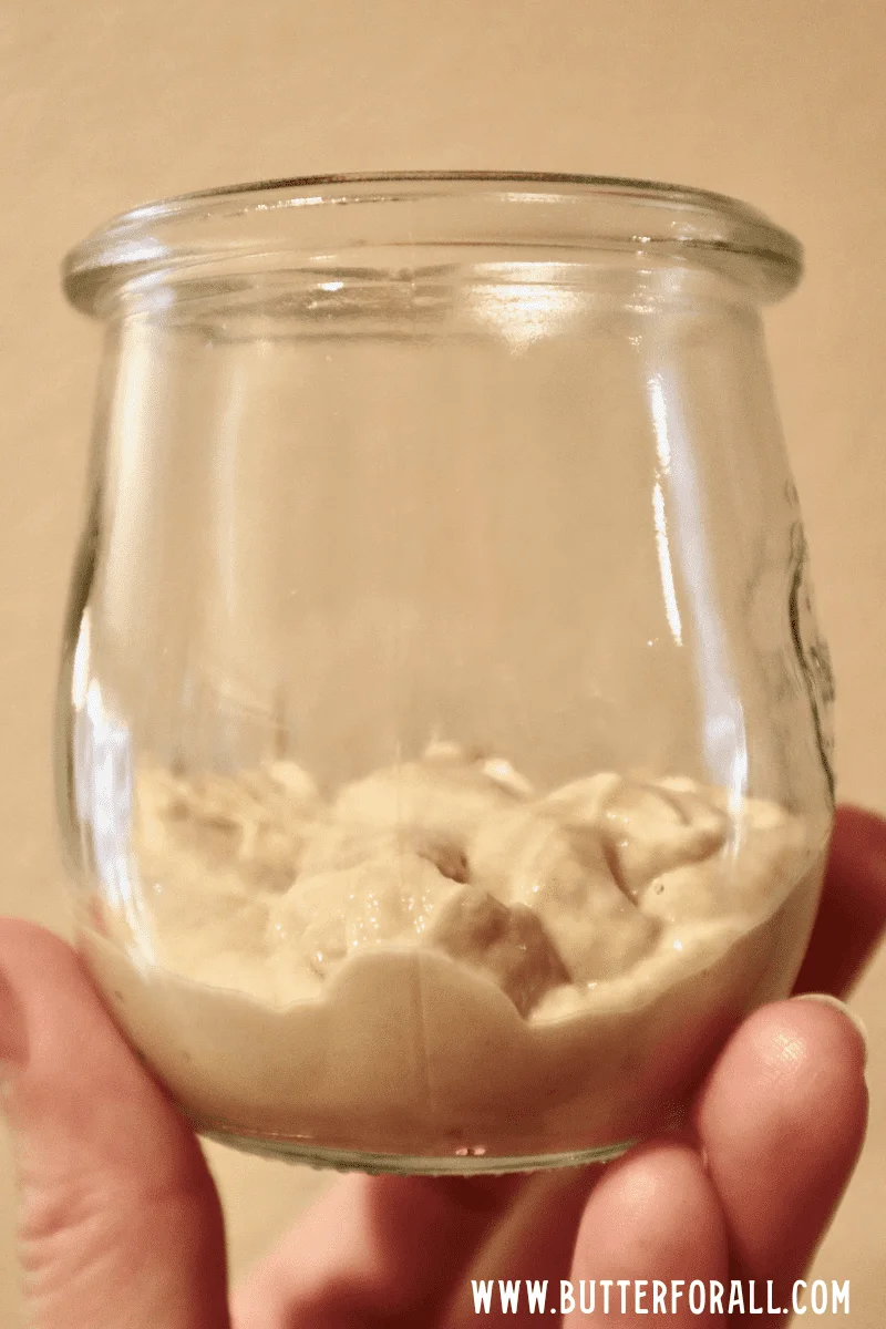 A small jar 1/3 filled with fresh sourdough starter.