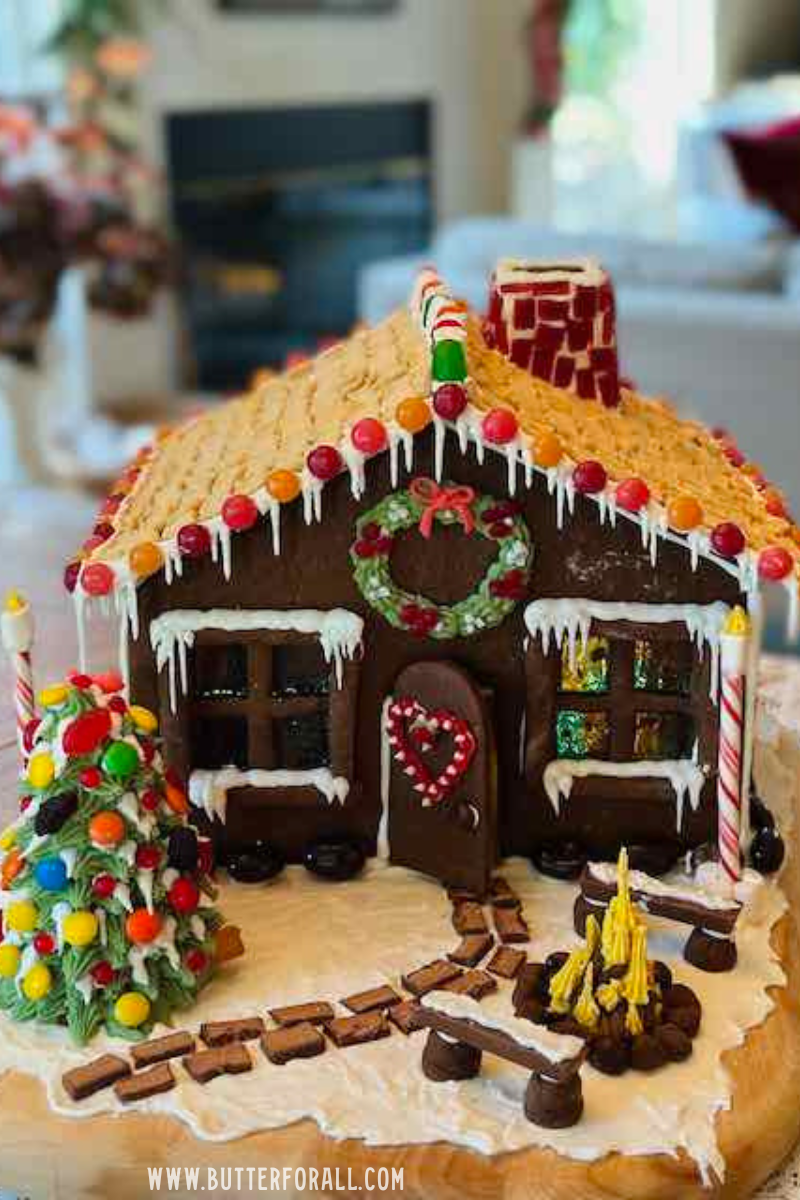 A festive, fully decorated gingerbread house complete with trees, path, fire, and lampposts.