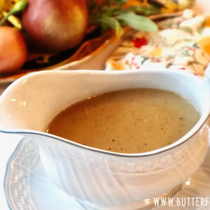 A white gravy boat full of golden-brown gravy that has been thickened with sourdough starter.